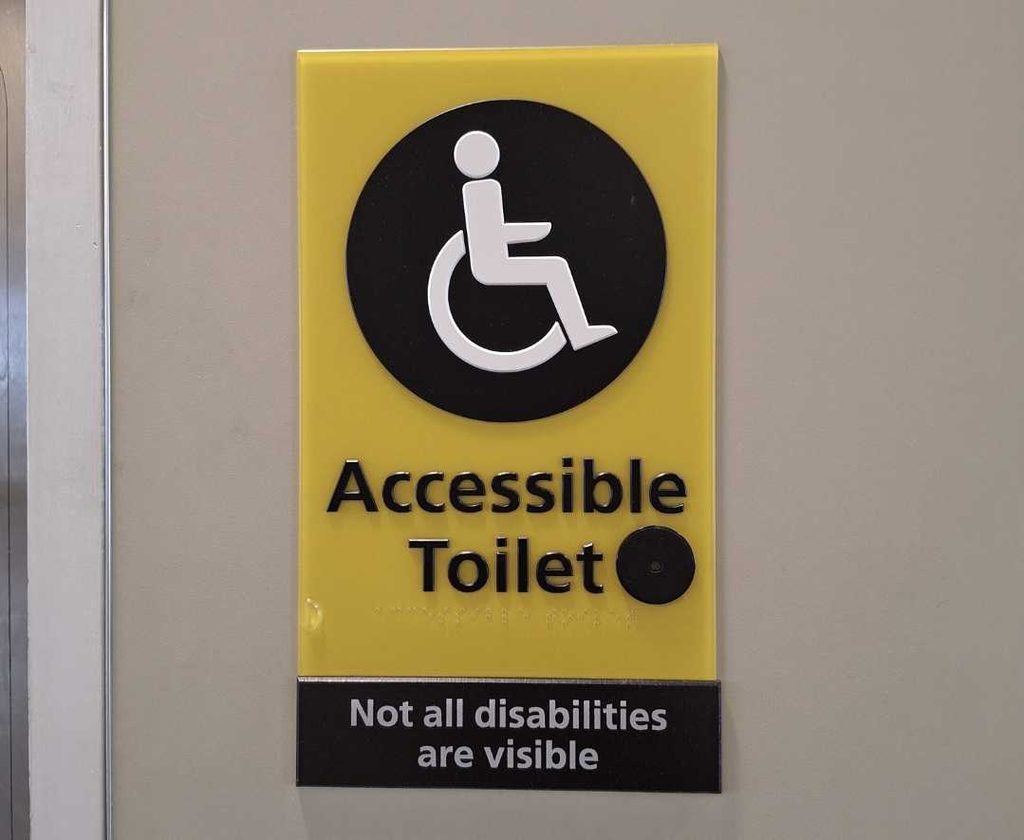 An accessible toilet sign that reads "not all disabilities are visible".